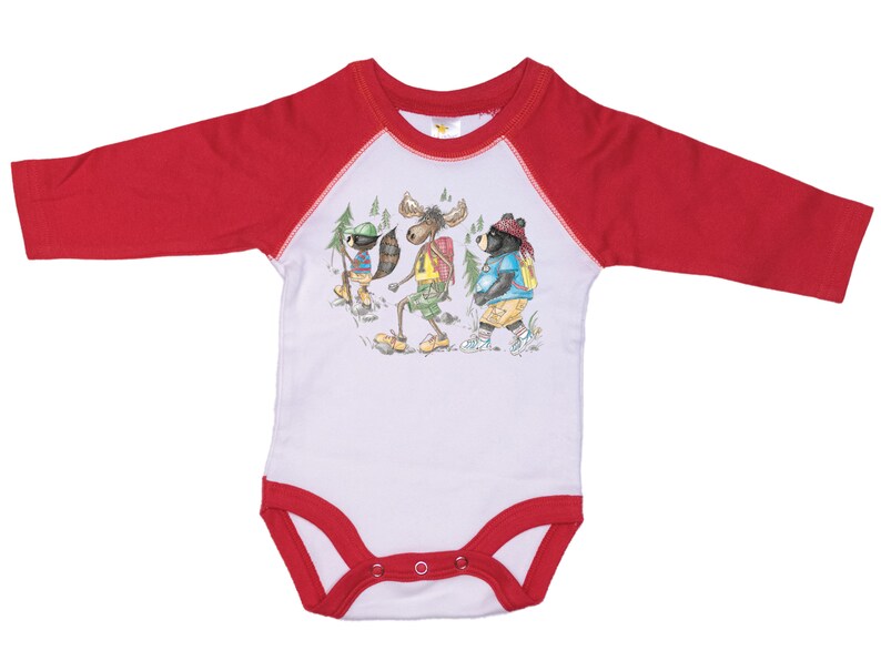 May include: White long-sleeve baby onesie with red raglan sleeves. The onesie features a graphic of a raccoon, moose, and bear wearing backpacks and hiking.