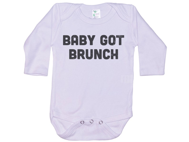 May include: White long-sleeve baby onesie with black text that reads "BABY GOT BRUNCH".