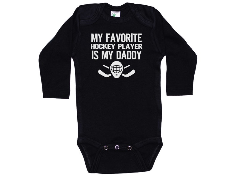 May include: Black long-sleeve baby onesie with white text that reads "My favorite hockey player is my daddy" and a hockey stick and goalie mask graphic.