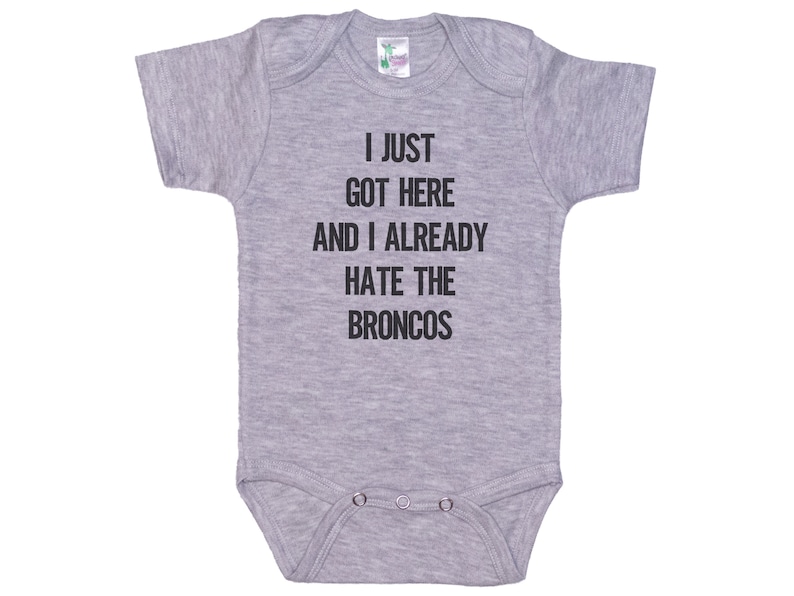 May include: Gray baby onesie with the text "I just got here and I already hate the Broncos" printed in black.