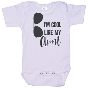 May include: A white baby onesie with short sleeves and a black graphic of sunglasses and the text "I'm cool like my aunt".