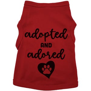 May include: Red dog tank top with black text that says "adopted and adored" with a black paw print inside a heart.