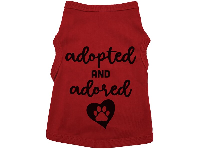 May include: Red dog tank top with black text that says "adopted and adored" with a black paw print inside a heart.