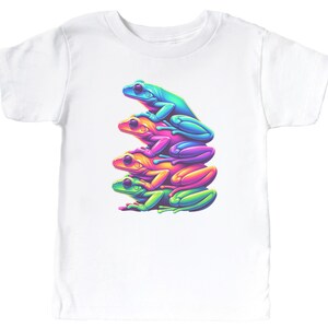 May include: A white t-shirt with a graphic of four frogs stacked on top of each other. The frogs are different colors: green, blue, pink, and yellow.