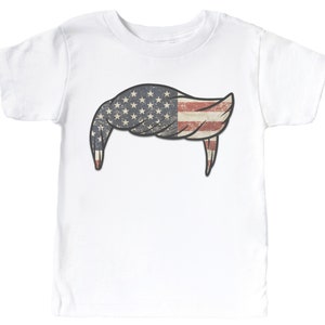 Pode incluir: Camiseta branca com um gr&aacute;fico de um penteado em forma da bandeira americana.