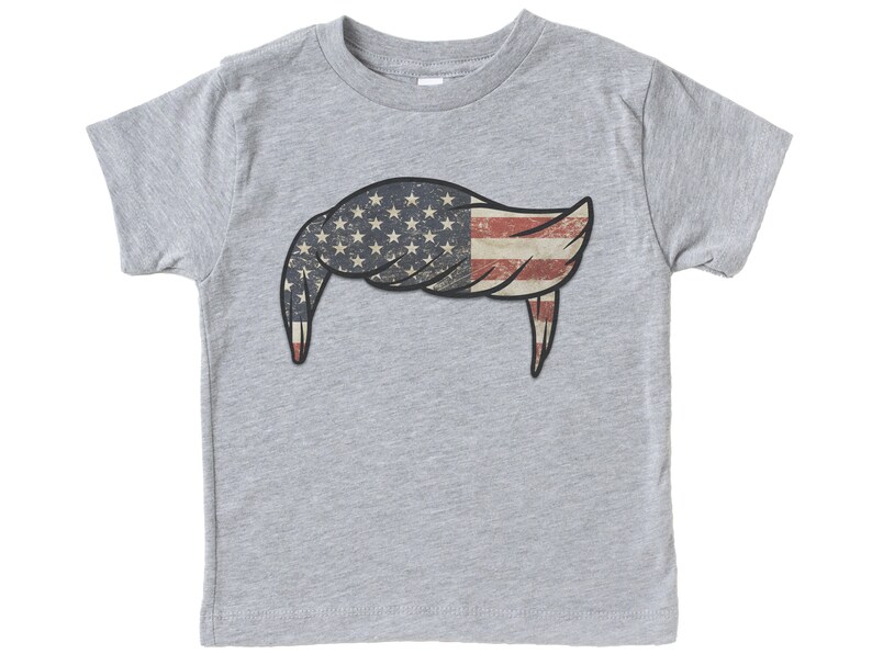 Pode incluir: Uma camiseta cinza com um design de bandeira americana vintage em forma de bigode.