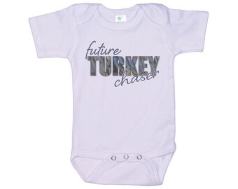Könnte beinhalten: Weißer Baby-Strampler mit kurzen Ärmeln und einem grafischen Aufdruck mit der Aufschrift "future TURKEY chaser" in schwarzer und grauer Schrift mit einem Truthahnfedermuster.
