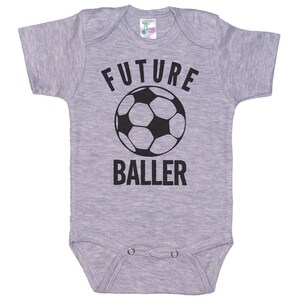 May include: Gray baby onesie with black text that reads "FUTURE BALLER" and a black and white soccer ball graphic.