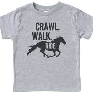 May include: Gray short-sleeved t-shirt with a black silhouette of a horse running and the text "Crawl. Walk. Ride."