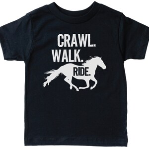 May include: A black t-shirt with white text that reads "Crawl. Walk. Ride." and a white silhouette of a horse running.