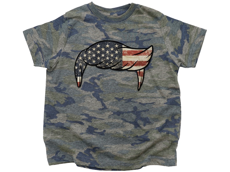 Pode incluir: Uma camiseta camuflada com um design de bandeira americana desbotada em forma de penteado.
