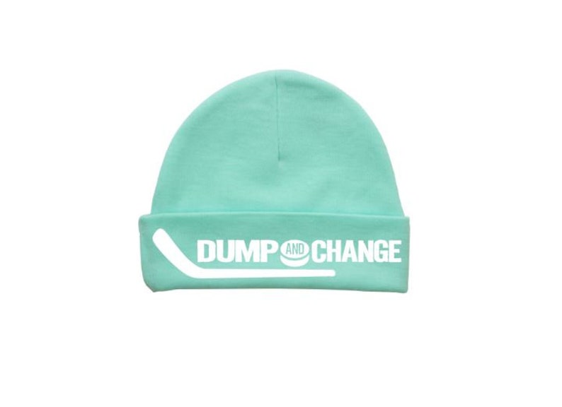 May include: A turquoise blue beanie with a white hockey stick and puck graphic and the text "DUMP AND CHANGE".