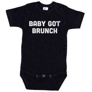 May include: Black baby onesie with white text that reads "BABY GOT BRUNCH".