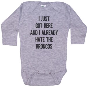 May include: Gray long-sleeve baby onesie with the text "I just got here and I already hate the Broncos".