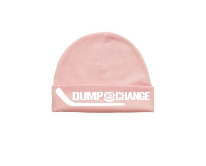 May include: Pink beanie with a white hockey stick and puck graphic and the text "DUMP AND CHANGE".