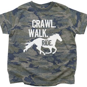 May include: A camouflage-patterned t-shirt with the text "Crawl. Walk. Ride." and a white silhouette of a horse running.