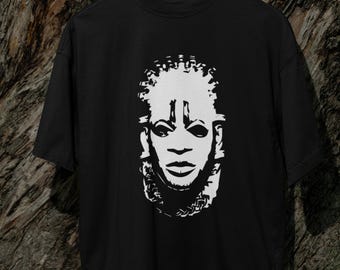 Puede incluir: Camiseta negra con un gráfico blanco de una máscara africana estilizada.