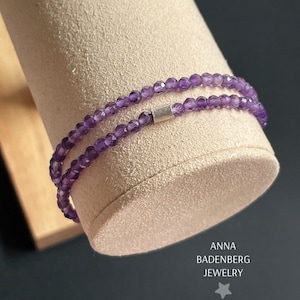 Könnte beinhalten: Ein doppelreihiges Amethyst-Armband mit einem silbernen Verschluss. Das Armband befindet sich auf einem Präsentationsständer. Der Text "ANNA BADENBERG JEWELRY" ist unterhalb des Armbands sichtbar.