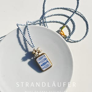 Necklace: Ceramic pendant with fish motif and Java pearl tassel on a Preciosa glass bead necklace in blue and white, cultured pearl, maritime style.