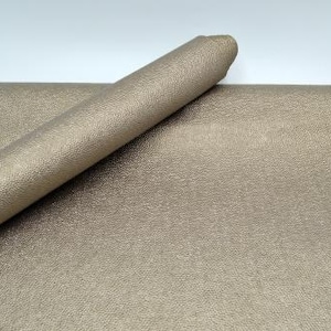 Könnte beinhalten: Eine Rolle Metallic-Gold-Kunstlederstoff mit strukturierter Oberfläche.