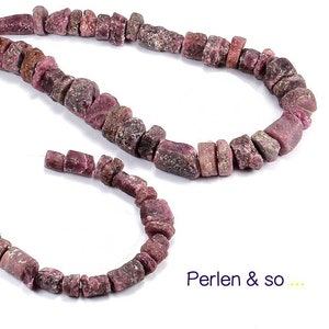 Könnte beinhalten: Zwei Stränge grob geschnittener, rot-violetter Edelsteinperlen. Die unregelmäßig geformten Perlen sind zu einer Halskette und einem Armband aufgereiht. Der Text "Perlen & so ..." ist sichtbar.