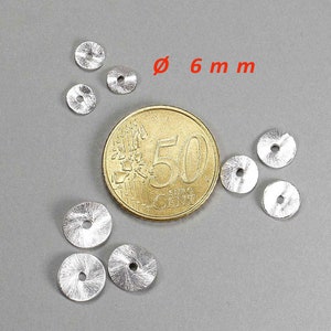 May include: A collection of small, silver-colored, circular metal beads, each with a central hole. The beads are approximately 0.24 inches in diameter. A Euro coin is included for size comparison, set against a gray background.