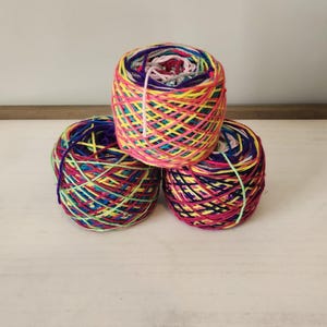 May include: Three balls of colorful yarn, each with a different color combination. The yarn is a mix of pink, yellow, blue, green, and purple.