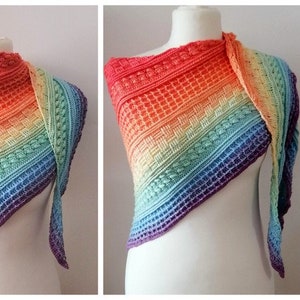 Può includere: Uno scialle all'uncinetto arcobaleno con un motivo a punto testurizzato e frange lunghe. Lo scialle è esposto su un manichino bianco.