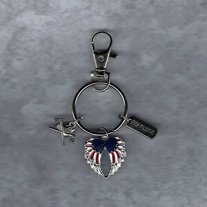 May include: Silver keychain with a red, white, and blue American flag wing charm, a silver charm with an axe and a silver tag that says "Fearless".