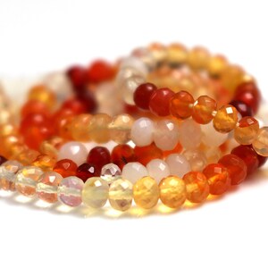 May include: A strand of faceted opal beads in shades of orange, yellow, and white. The beads are arranged in a loose pile, showing the different colors and facets.