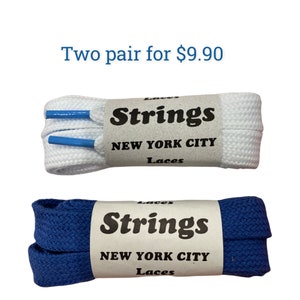 May include: Two pairs of shoelaces, one white and one blue, with the brand name "Strings New York City Laces" printed on the label.