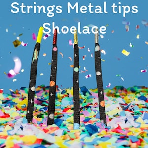 May include: Four colorful shoelaces with metal tips and a space-themed design. The shoelaces are against a blue background with confetti.