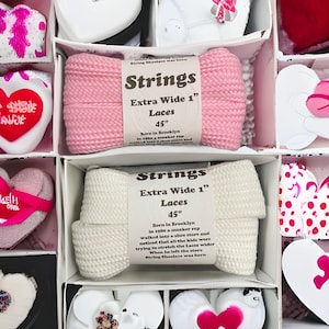 May include: Two pairs of extra wide shoelaces in pink and white. The shoelaces are 45 inches long and are packaged in a white box with a black label that says "Strings Extra Wide 1" Laces 45"  Born in Brooklyn in 1980 a sneaker rep walked into a shoe store and noticed that all the kids were trying to stretch the Laces wider When he left the store String Shoelace was born"