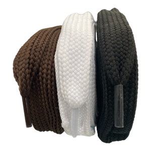 May include: Three pairs of shoelaces in brown, white and black. The shoelaces are made of a woven material and have a flat, rounded shape.