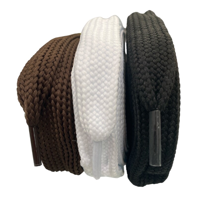 May include: Three pairs of shoelaces in brown, white and black. The shoelaces are made of a woven material and have a flat, rounded shape.