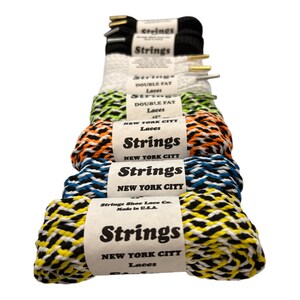 May include: Assortment of colorful shoelaces with the brand name "Strings New York City" printed on the labels. The shoelaces are made in the USA.