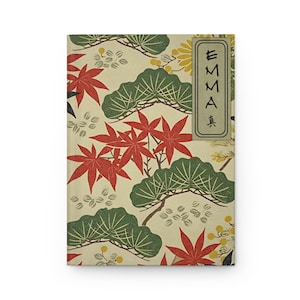 以下が含まれることがあります： 赤色のモミジの葉、緑色の松の枝、黄色の花が描かれた、クリーム色のノート。表紙には黒い文字で「EMMA」と書かれている。