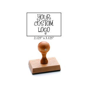 May include: Wooden self-inking stamp with a rectangular base and a round handle. The stamp is 2.125 inches by 3.125 inches and has the text "YOUR CUSTOM LOGO" on it.
