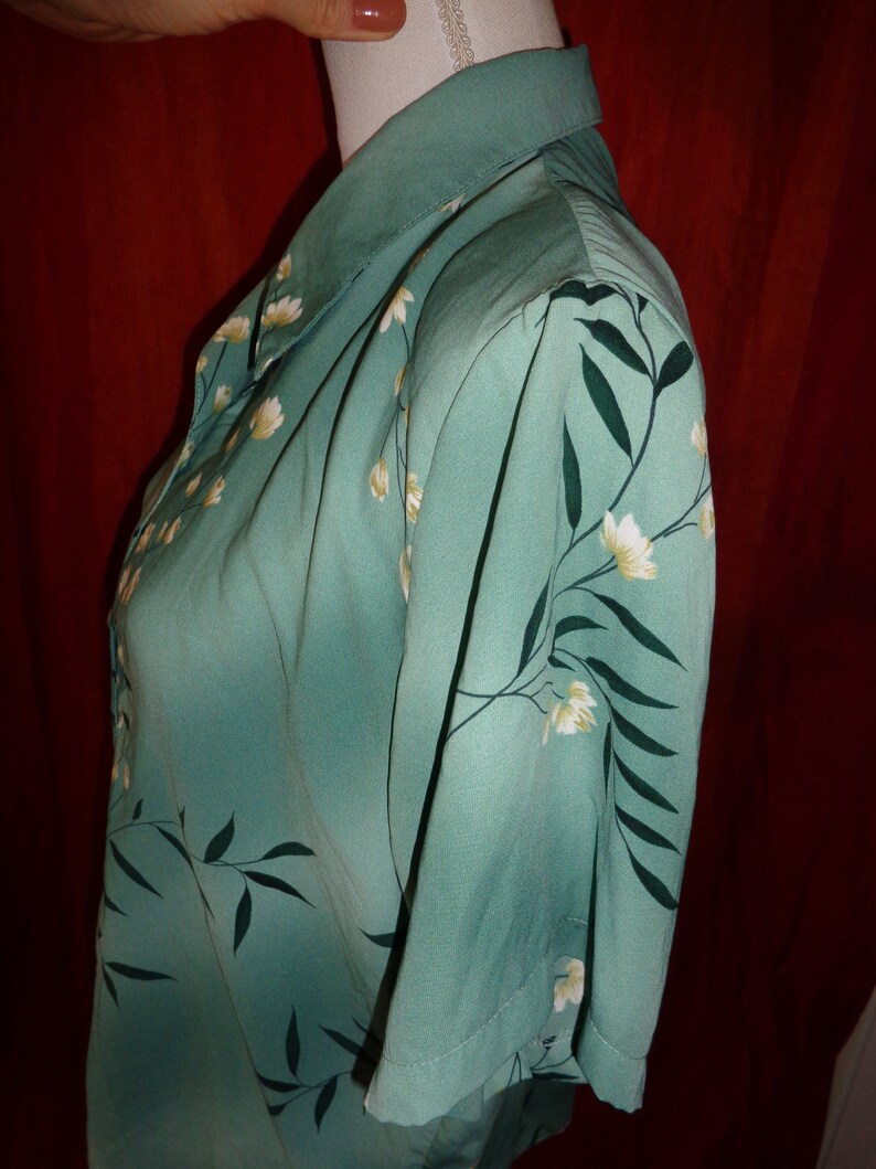 K&ouml;nnte beinhalten: Ein kurz&auml;rmeliges, knopfverschlossenes Hemd in Tealblau mit einem wei&szlig;en Blumenmuster. Das Hemd hat einen Kragen und eine lockere Passform.