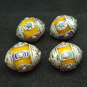 以下が含まれることがあります： 銀と青色のエナメル細工が施された、黄色の丸いビーズが4つ。それぞれのビーズは異なるデザインで、小さなターコイズストーンが特徴です。