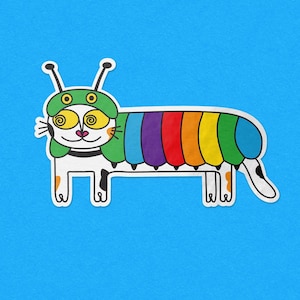 Op de afbeelding: Een grillige illustratie van een kat-rups hybride tegen een blauwe achtergrond. Het wezen heeft een wit lichaam met zwarte vlekken, een groene hoed met antennes en een regenboogkleurige, gesegmenteerde rug. De ogen zijn wervelend en geel.