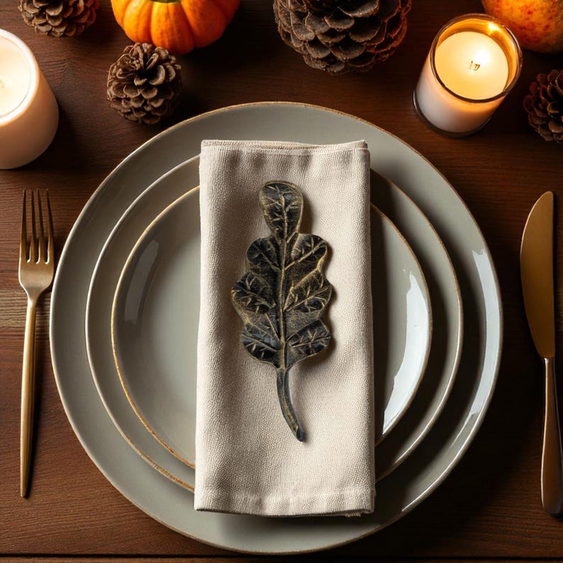 Hand-forged oak leaf in black finish on linen napkin, close-up.