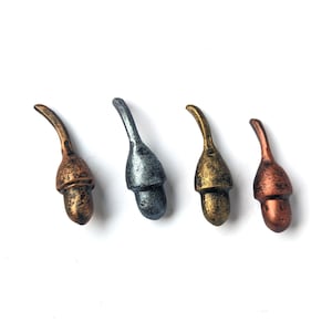 May include: Four acorn-shaped bottle stoppers in varying metallic finishes: bronze, silver, gold, and copper. Each stopper has a curved stem and a textured cap, displayed against a white background. These decorative stoppers add a unique touch to any bottle.