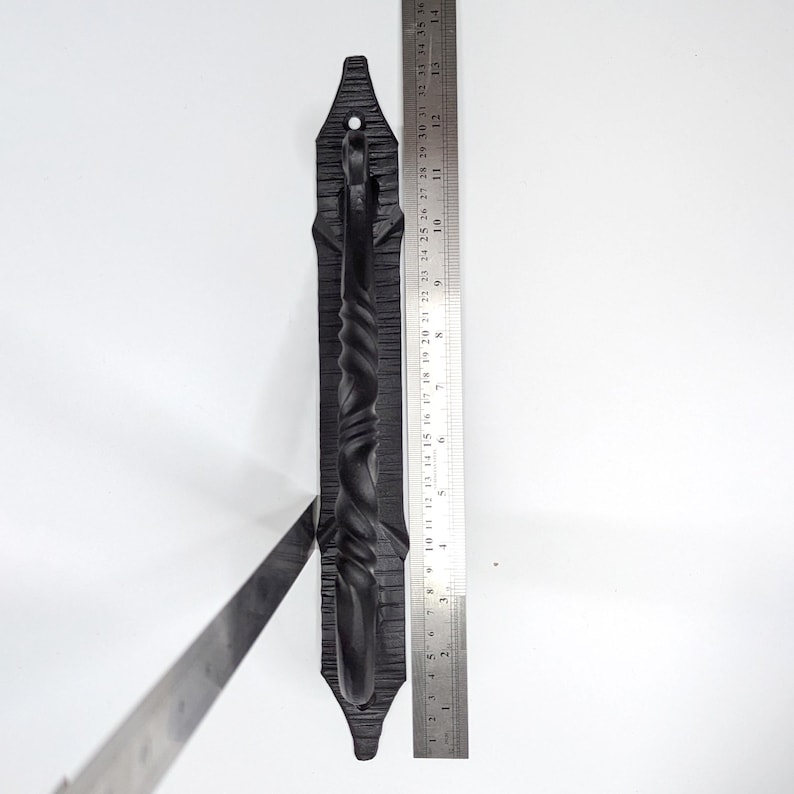 K&ouml;nnte beinhalten: Schwarzer Schmiedeeisener T&uuml;rgriff mit einem gedrehten Design. Der Griff ist etwa 25 cm lang und auf einer flachen Platte montiert.