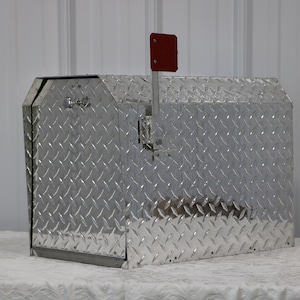 May include: A silver mailbox with a diamond plate pattern and a red flag. The mailbox is made of metal and has a secure lock.