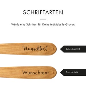 Puede incluir: Dos cucharas de madera con el texto "Wunschtext" grabado en ellas. La cuchara superior tiene el texto en una fuente cursiva, etiquetada como "Schreibschrift". La cuchara inferior tiene el texto en una fuente de bloque, etiquetada como "Druckschrift".
