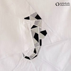 May include: A white fabric background with a black and gray geometric design of a seahorse. The design is made of fabric pieces sewn together.