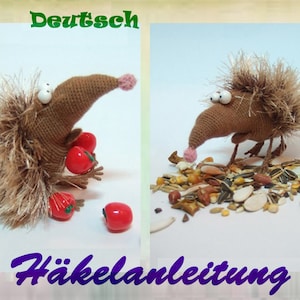 Pode incluir: Um ouriço de crochê castanho com um nariz rosa e grandes olhos brancos segura contas vermelhas. O ouriço está sentado em uma superfície branca com um monte de sementes de pássaro no fundo. O texto "Deutsch Häkelanleitung" é visível na imagem.