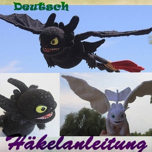 May include: Crochet pattern for a black and white dragon. The pattern includes instructions for making a black dragon with red wings and a white dragon with white wings. The pattern is written in German.