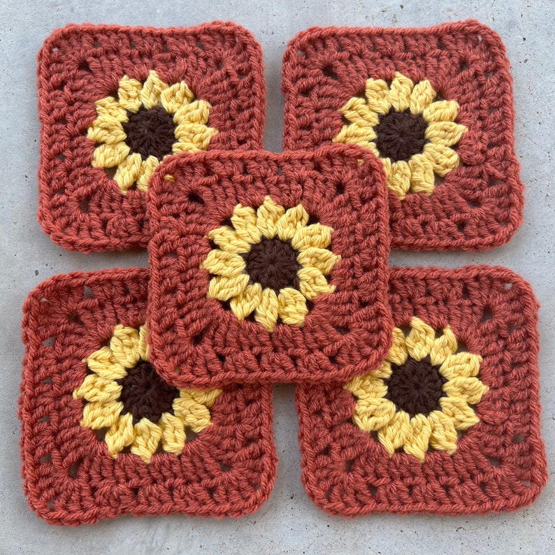 May include: Five crocheted sunflower squares in shades of brown, yellow, and orange. The squares are arranged in a flower shape.